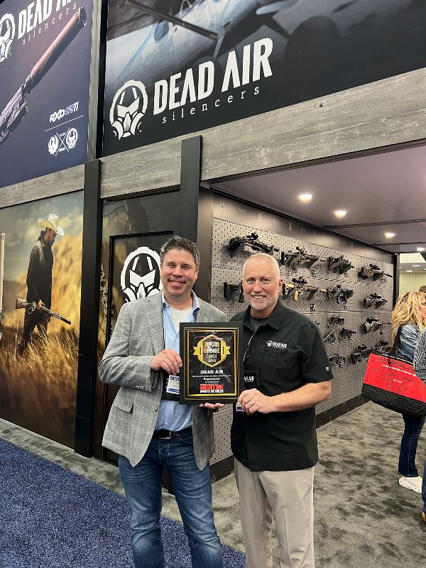 Two men holding award in front of display